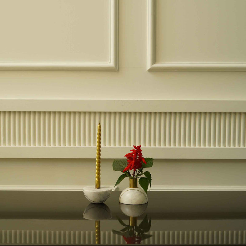 Two halves of a decorative marble sphere, one with a candle and other with a flower.