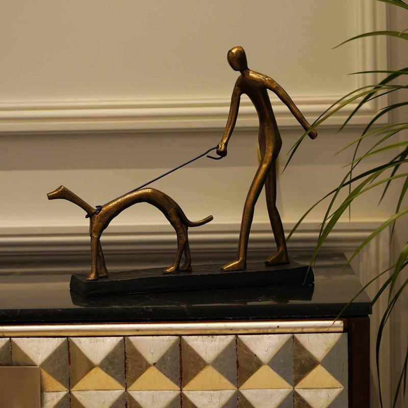 Table top metallic sculpture of a man walking a dog.