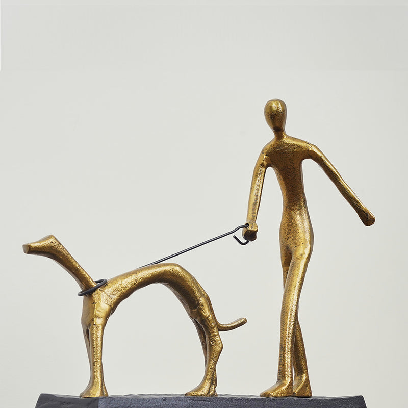 A metallic sculpture of a man walking a dog in a close-up angle