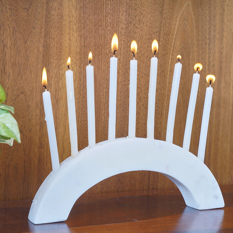 Side view of a white marble semi-circle slab as a candle holder with 9 burning candles.