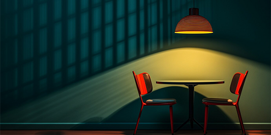 A lamp shade focusing light on a table and 2 chairs