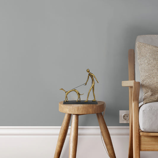 A metallic sculpture of a man walking a dog, placed on a side table