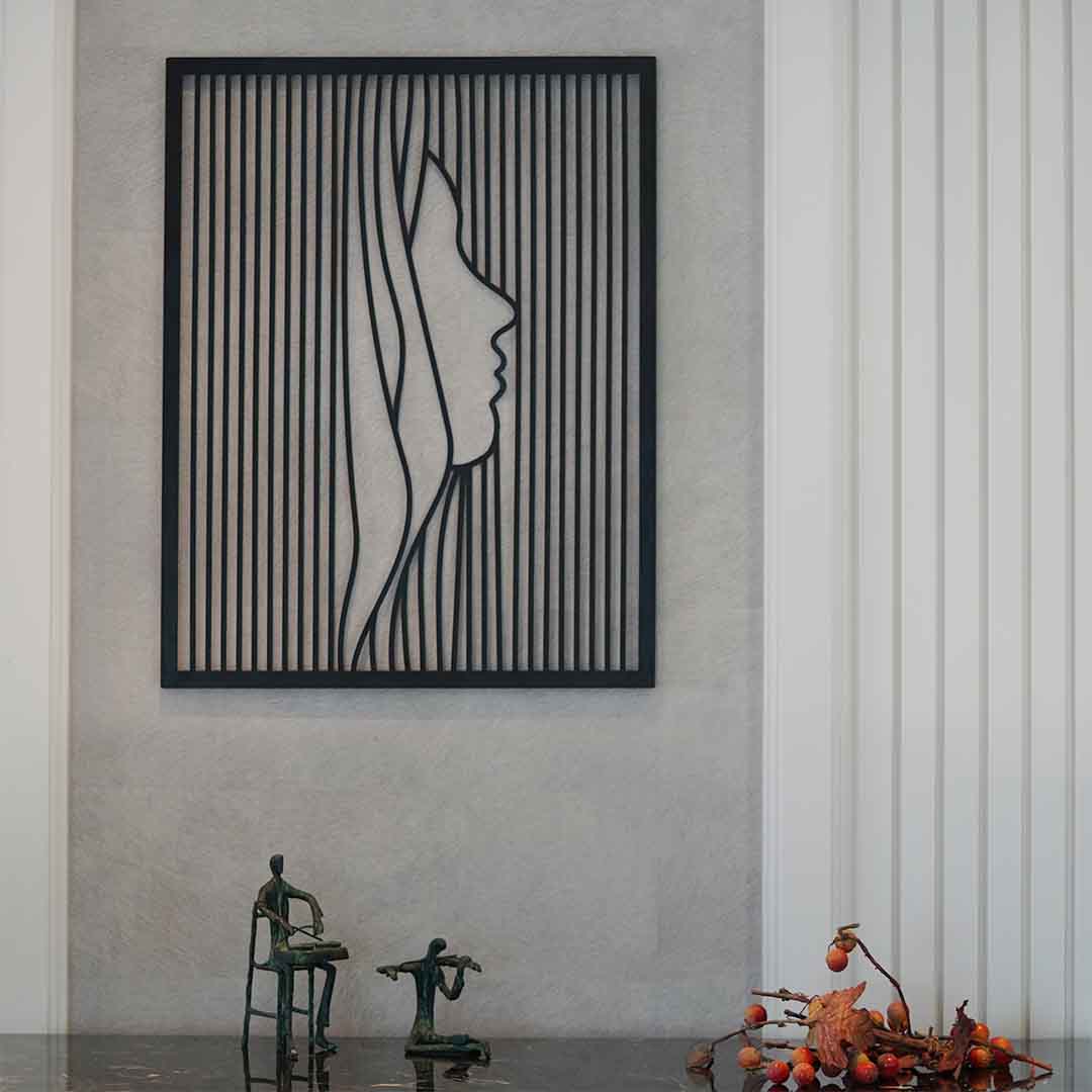 Large metallic black colored wall art showing face of a lady in modern design.