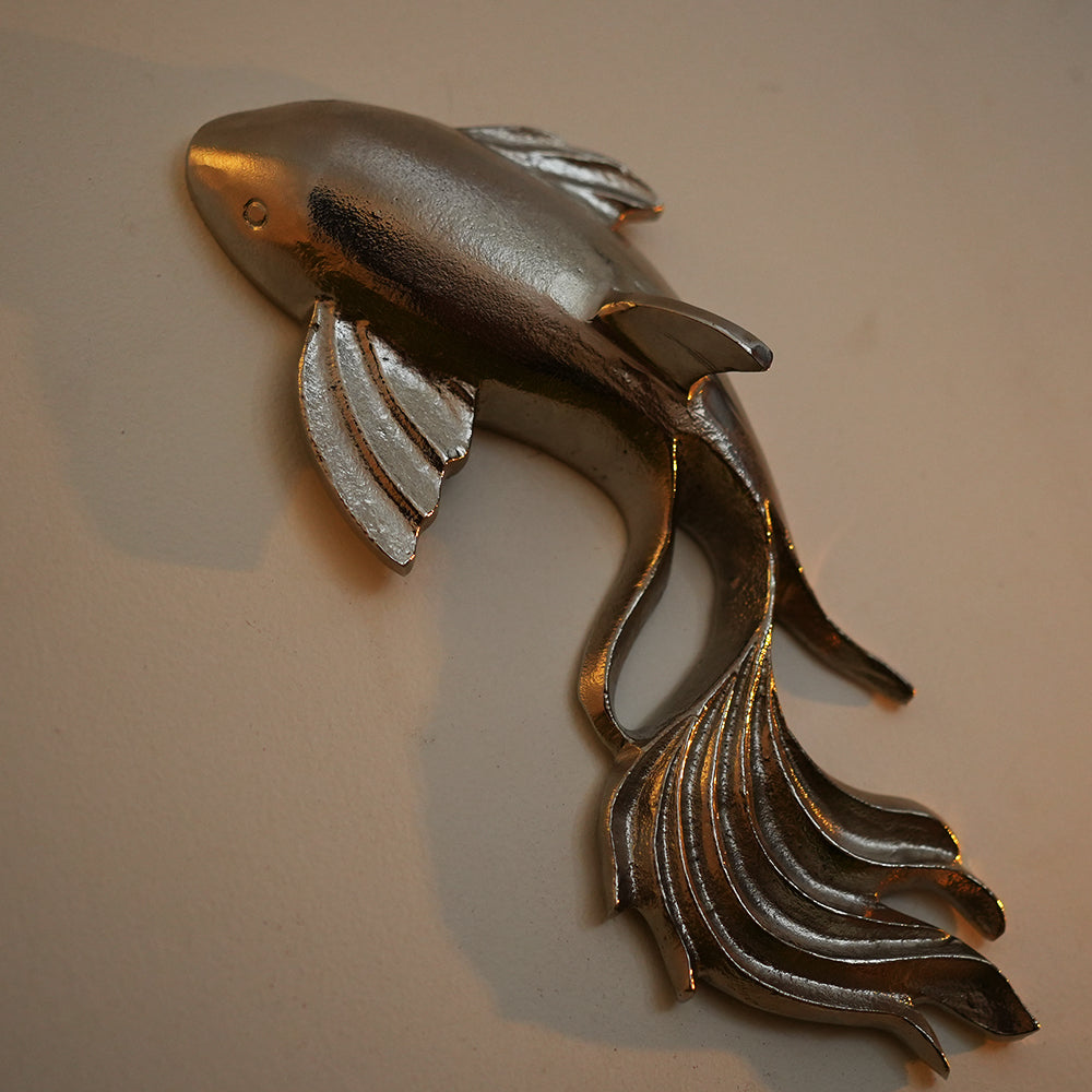 Close up image of a metallic wall art in fish shape and nickel chrome finish.