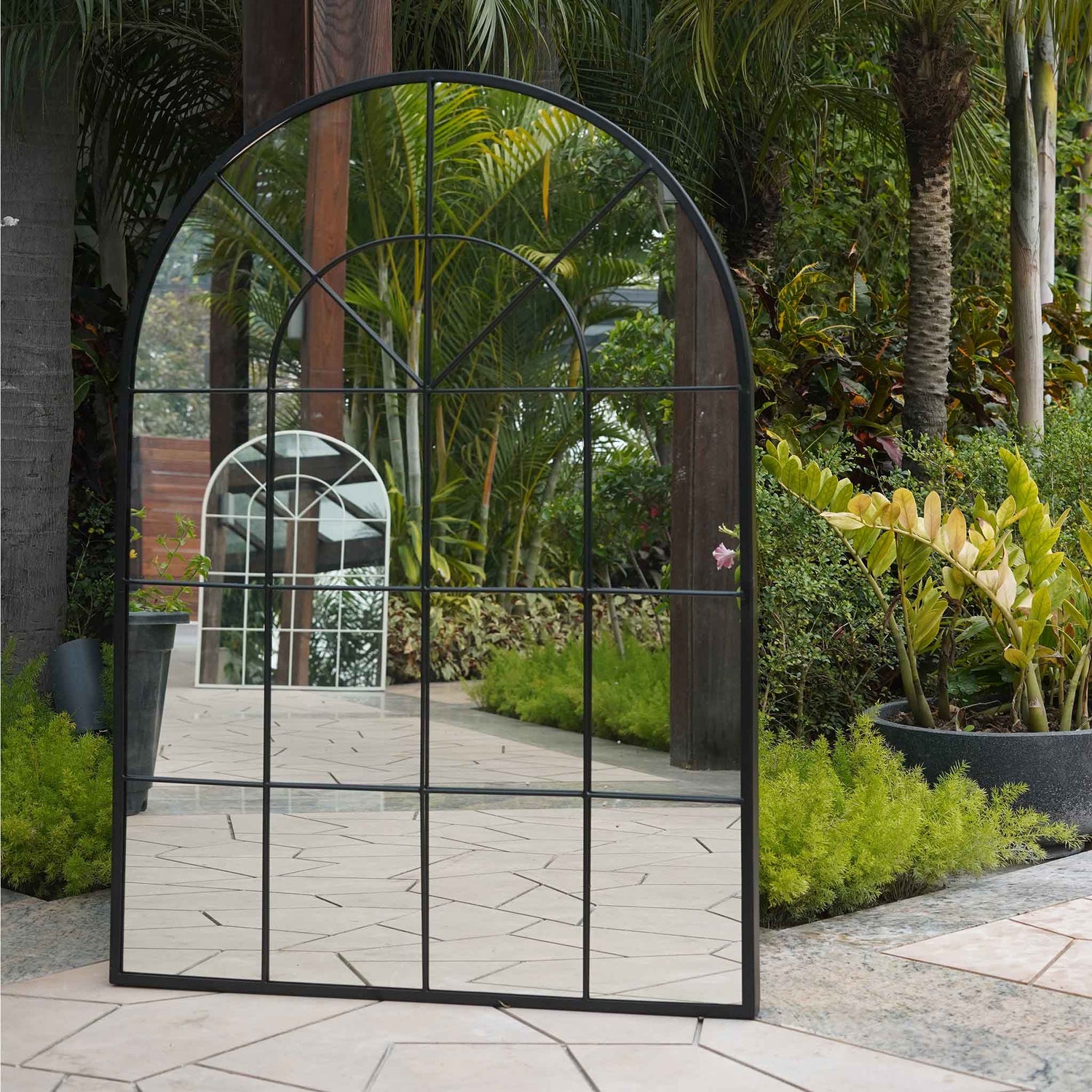 A large black metallic mirror in the shape of a window .