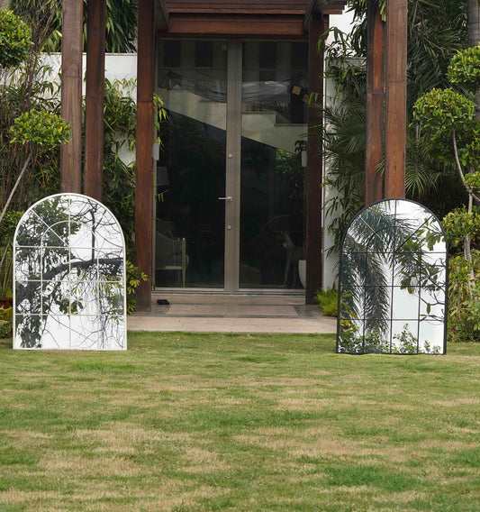 A black and a white large metallic mirror shaped like a window placed next to each other.