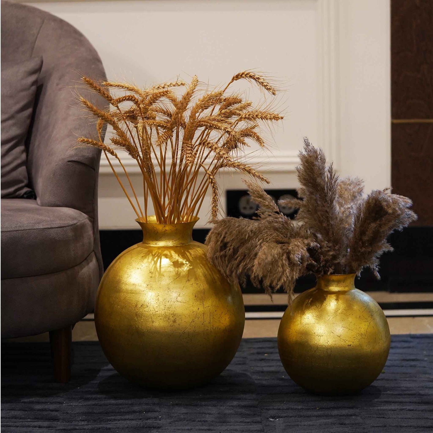 Two large metallic golden pot-shape vases placed on the floor.