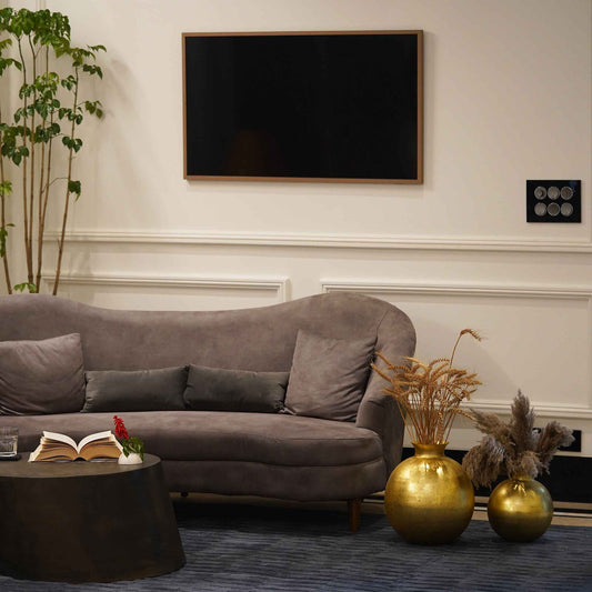 A living room with sofa, rug and table has two large metallic golden vases placed on the floor