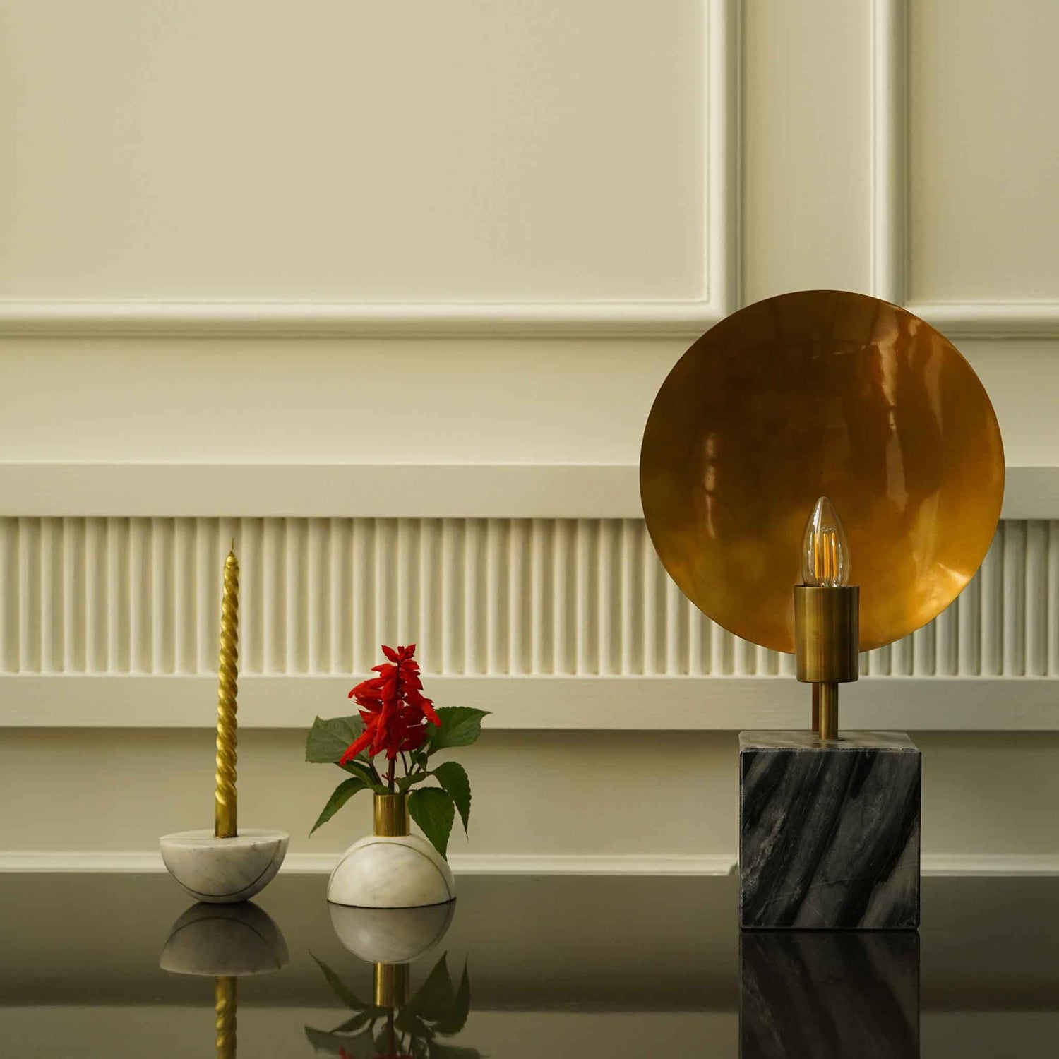A decorative spherical marble candle-cum-plant holder placed next to an artistic table lamp made out of concrete base.
