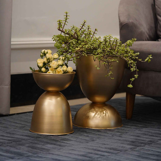 Set of 2 large planters in golden color, placed on the floor.