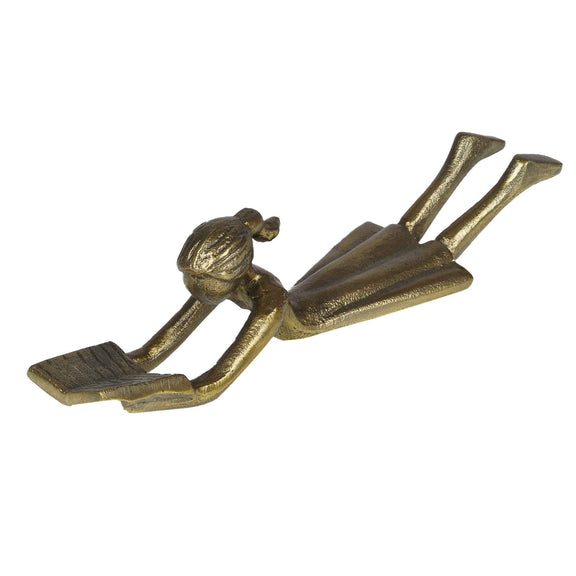 Table-top metallic decorative figurine with girl lying down and reading a book- side view and plain background