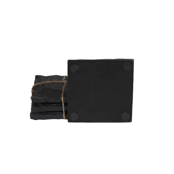 Four stacked square shaped black slate stone coasters in a plain background.
