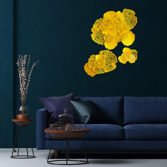 Set of 3 yellow metallic wall art in the design of bouquets of flowers hung on a dark blue wall in a living room.