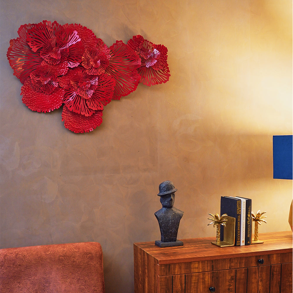 A red metallic wall art in the design of bouquets of flowers in a living room set-up.