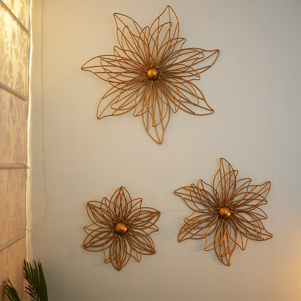 Set of 3 golden metal flowers for wall art arranged beautifully on a wall.