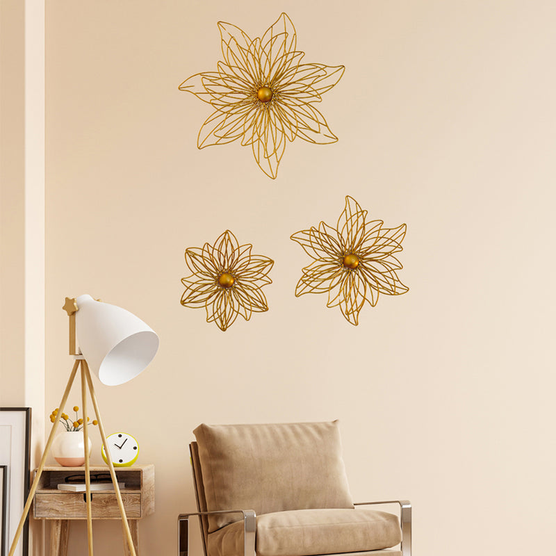 Set of 3 golden metal flowers for wall art arranged beautifully on a living room wall.