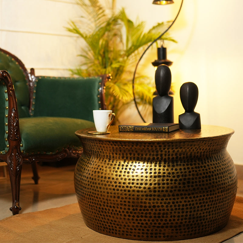 Handmade metallic round drum shape coffee table in antique copper finish is placed in a cozy living room.