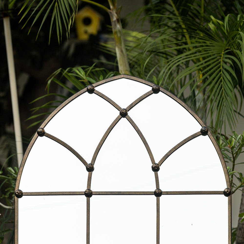 Close-up image of a large copper metallic mirror shaped like a dome window.