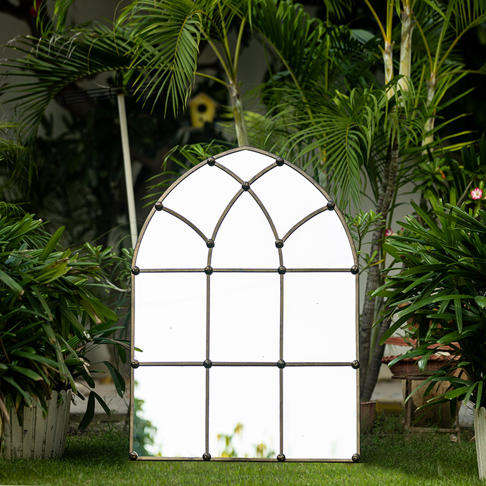 A large copper color metallic mirror in the shape of a dome window .