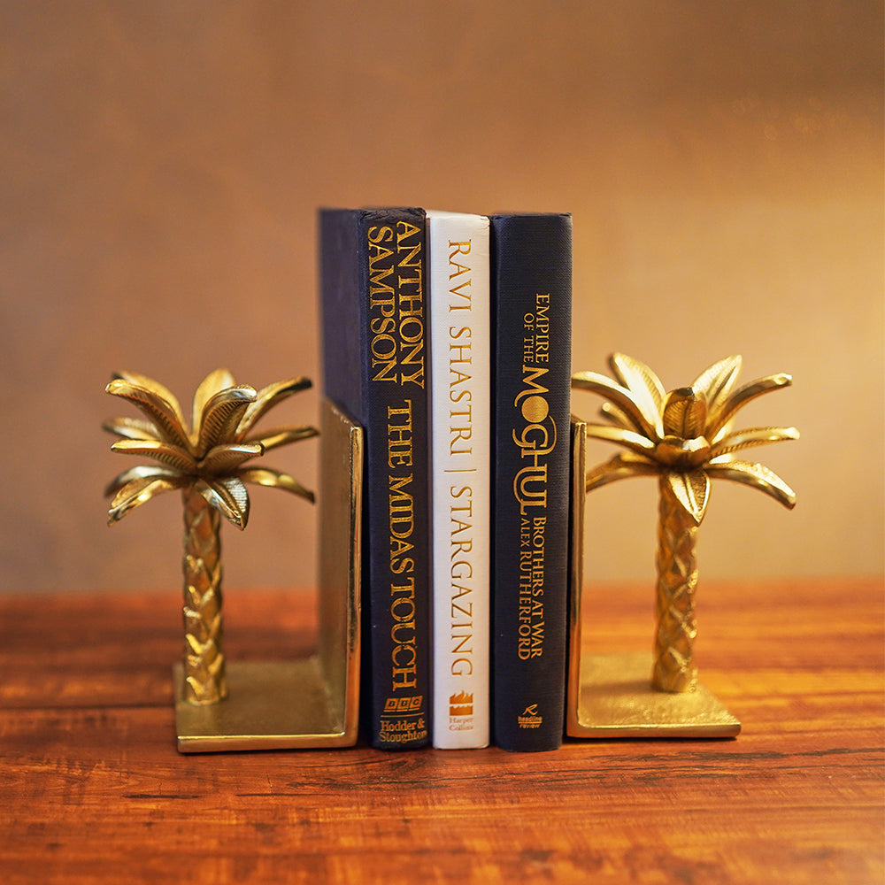 Golden metallic palm tree shaped bookends with 3 books placed in between.