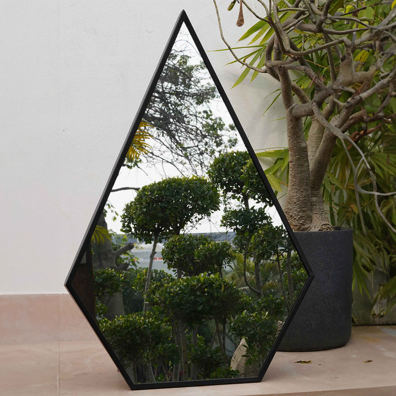 Close-up view of a tall metallic black pentagon framed mirror.