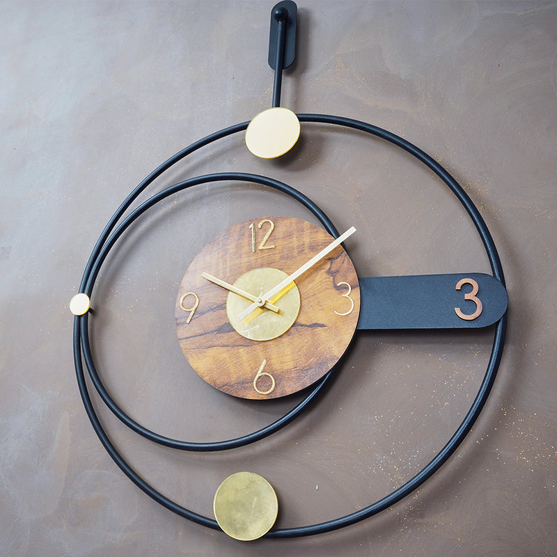 Side view of a large metallic wall clock in rings shape design, placed on a wall.