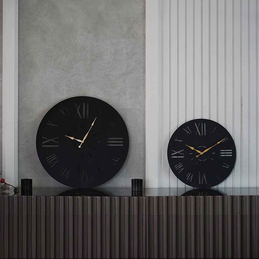 Two large black wall clocks in two sizes, with roman numerals placed on a console table.