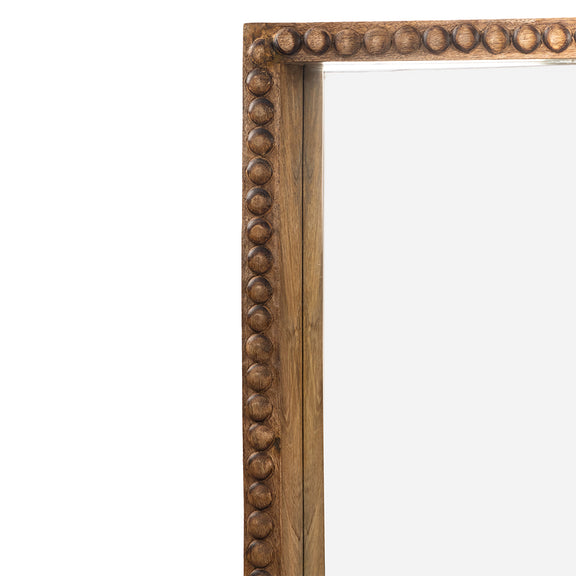 Large floor mirror in hand carved mango wood frame close-up front view in a white plain background.