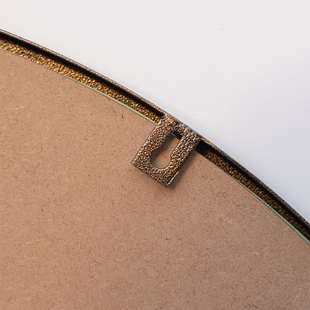 Close-up image of the hook of a metallic mirror used to mount the mirror on a wall.