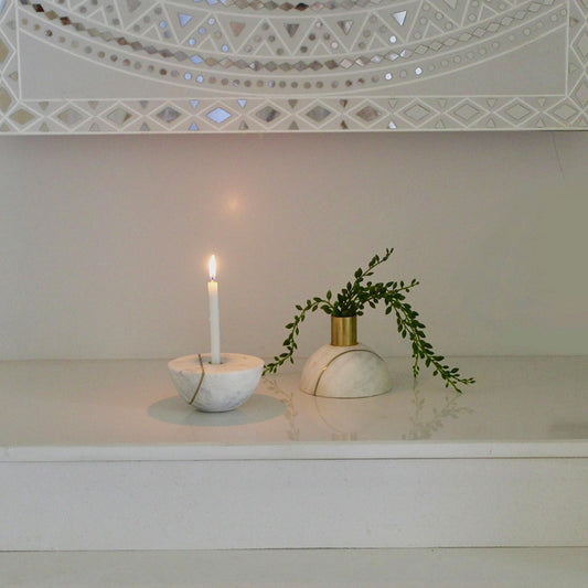 Two halves of a decorative marble sphere, one with a candle and other with a plant.