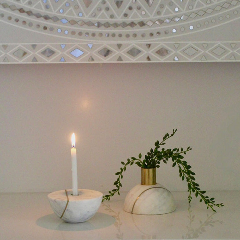 Two halves of a decorative marble sphere, one with a candle and other with a plant.