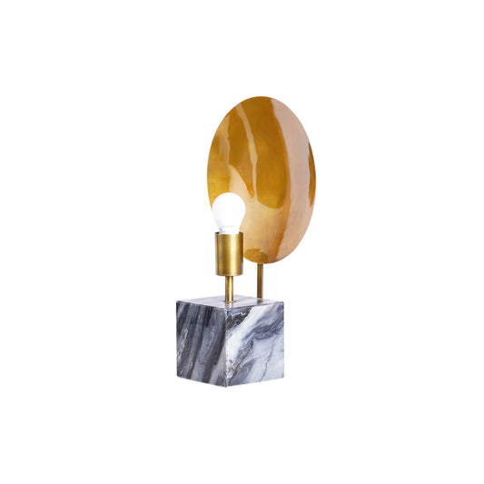 Side view of a modern design table lamp on a concrete base and a round metallic plate on the back of the bulb holder.