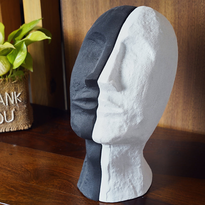 2 parts of a bookend set in the design of a human face split in half, one black and other white in color.