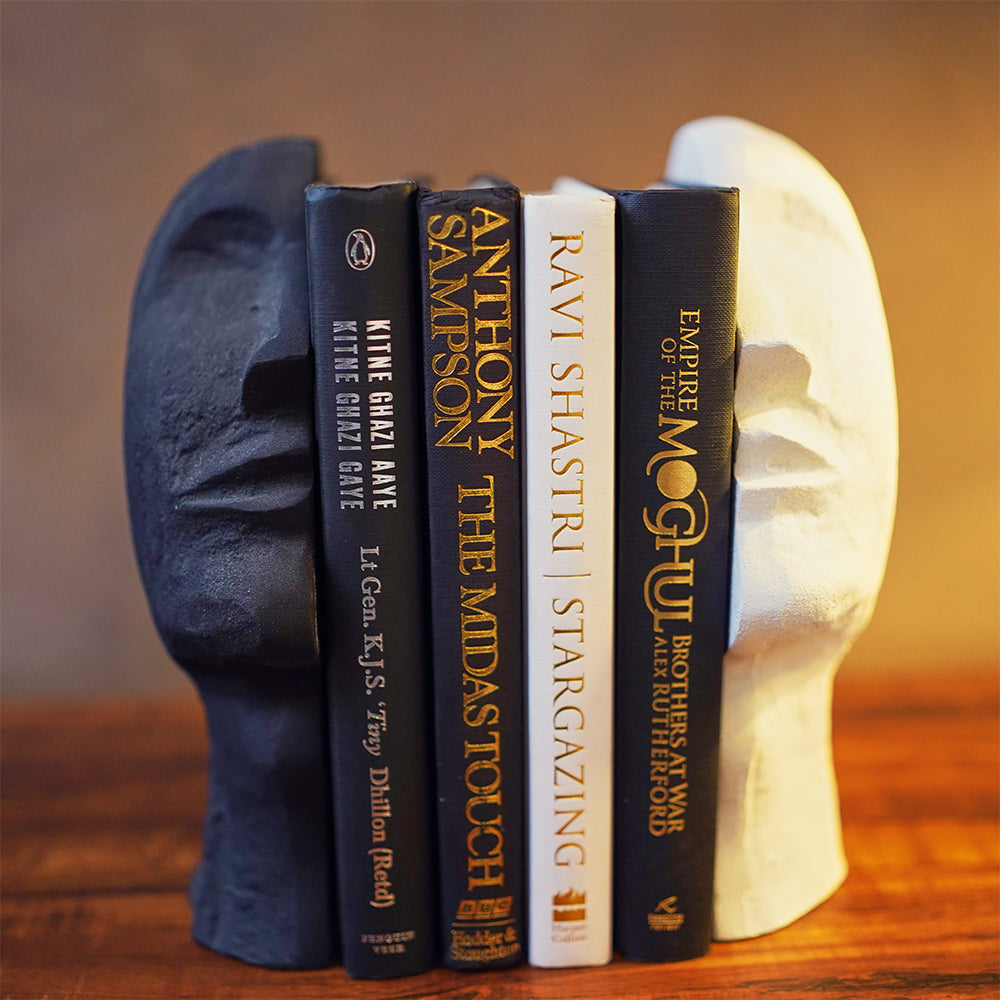 A bookend pair in the shape of an upward looking human face split in half with 4 books in between.