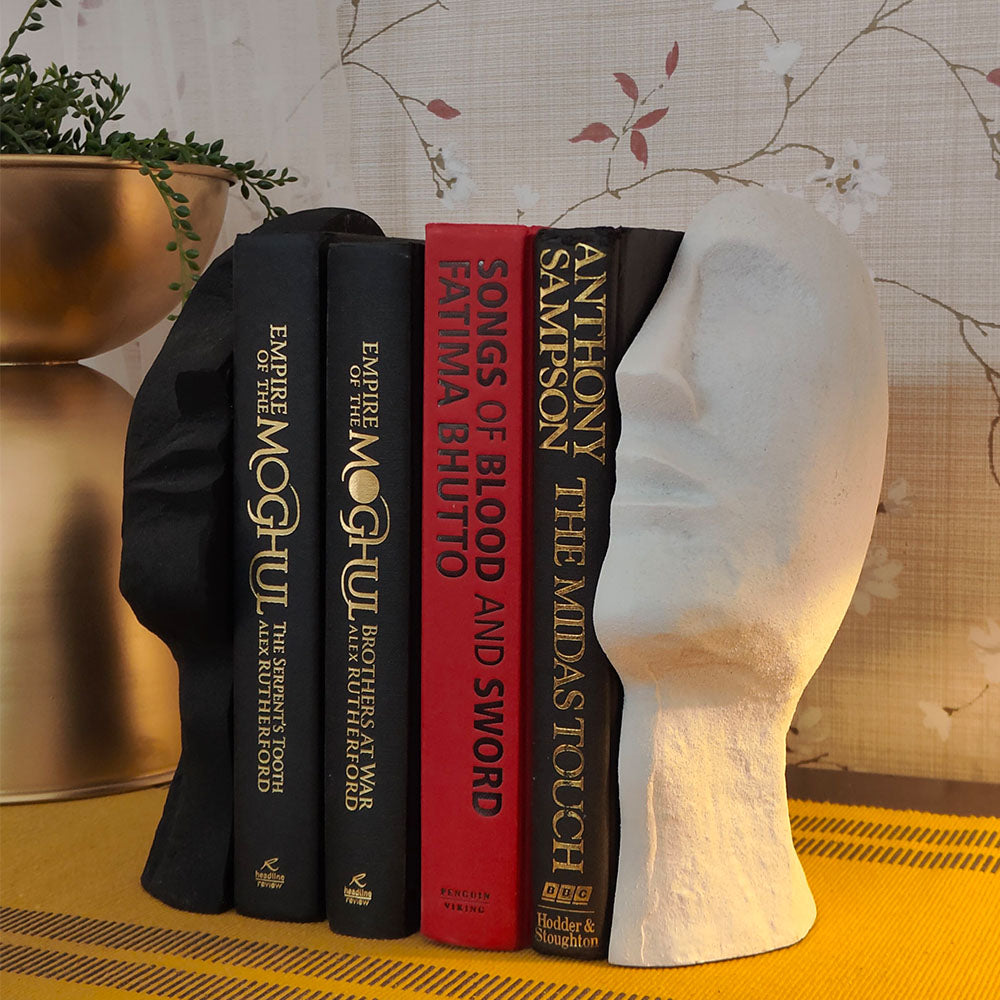 A bookend pair in the shape of an upward looking human face split in half with 4 books in between.