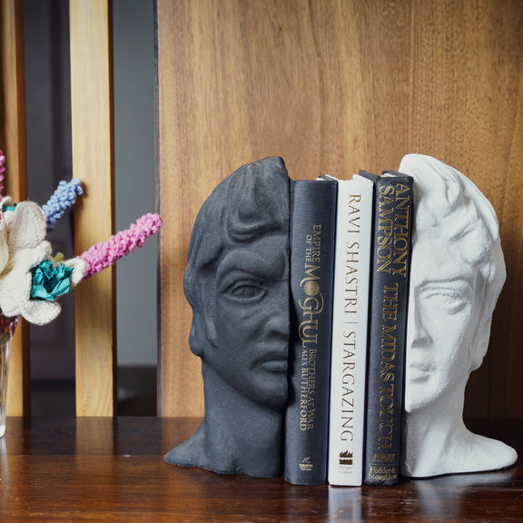 Modern bookends set with a man's face split in half, black and white color with 3 books in between.