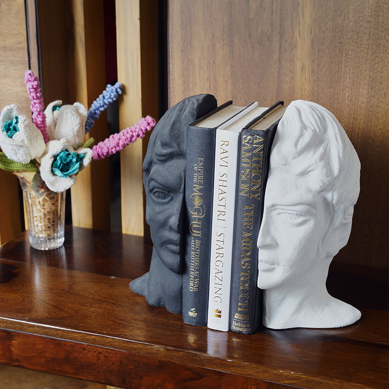 Modern bookends set with a man's face split in half, black and white color with 3 books in between at a side angle.