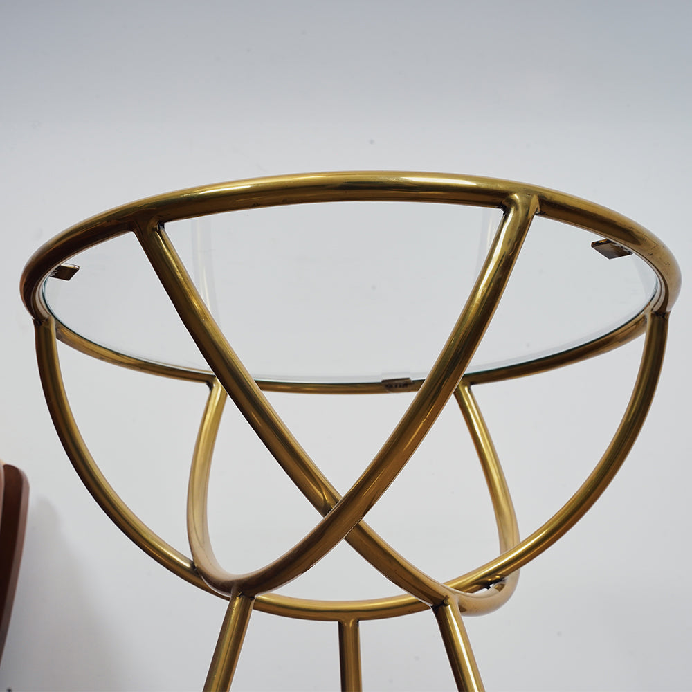 Bottom view of a side table with golden metallic legs and frame and a glass top.