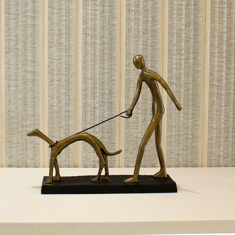 Table top metallic sculpture of a man walking his dog.