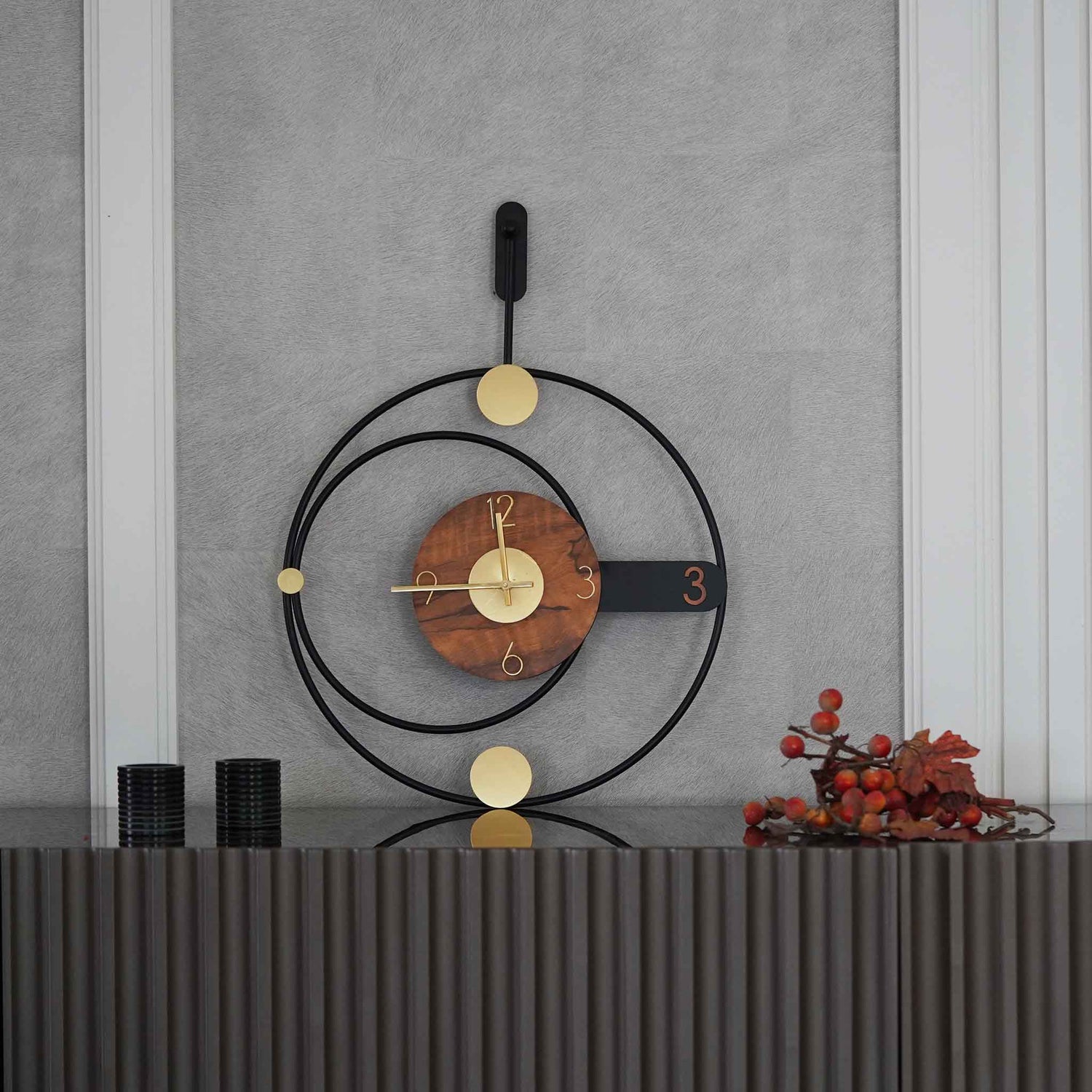 Modern design large metallic wall clock in rings shape design, placed on a console table.
