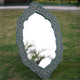 A traditional hand-carved mango wood long mirror placed in a garden setting