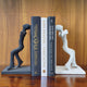 Human figures set of bookends, one black and other white, with 3 books placed in between.