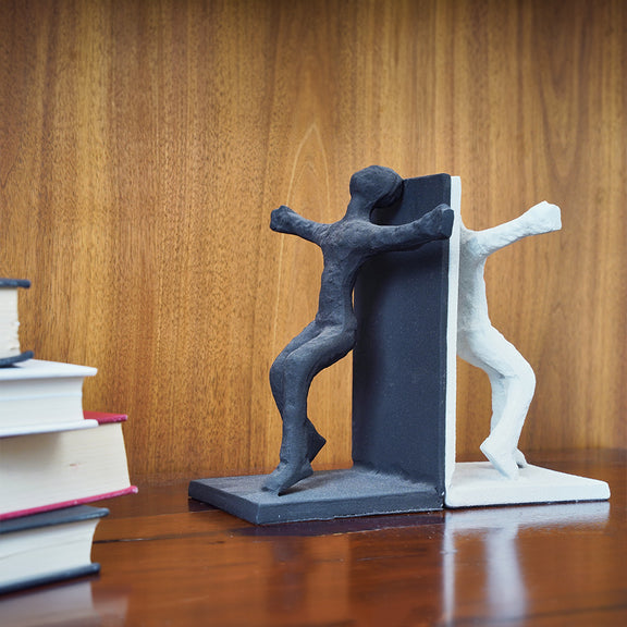 Human figures set of bookends, white one in front and other black on the back side, with books placed next to them.