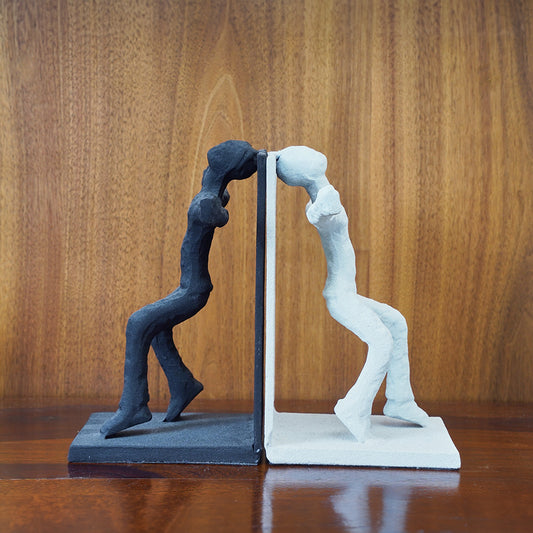 Human figures set of bookends, one black and other white  with backs against each other.