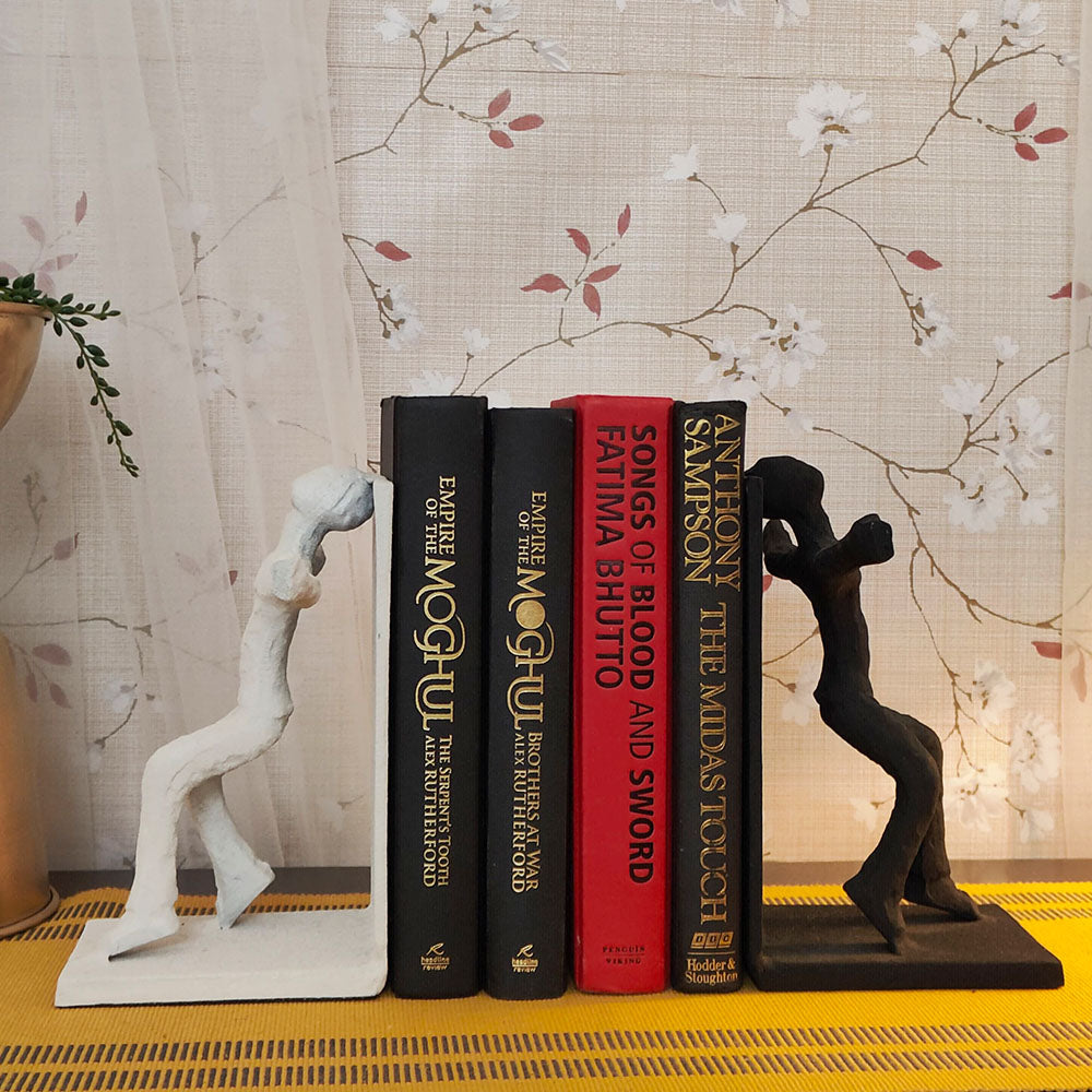 Human figures set of bookends, one black and other white, with 4 books placed in between.