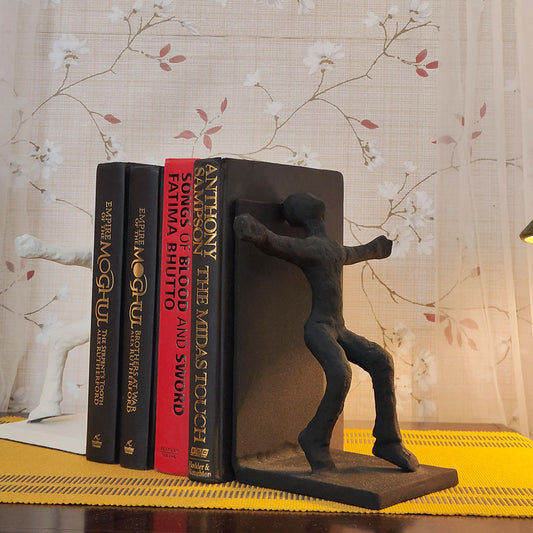 Human figures set of bookends, black one in front and other white on the back side, with 4 books placed in between.