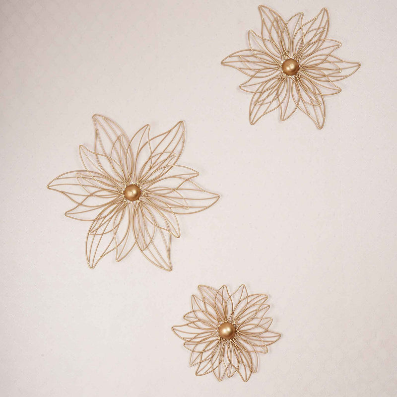 Set of 3 golden metal flowers for wall art on a plain background.