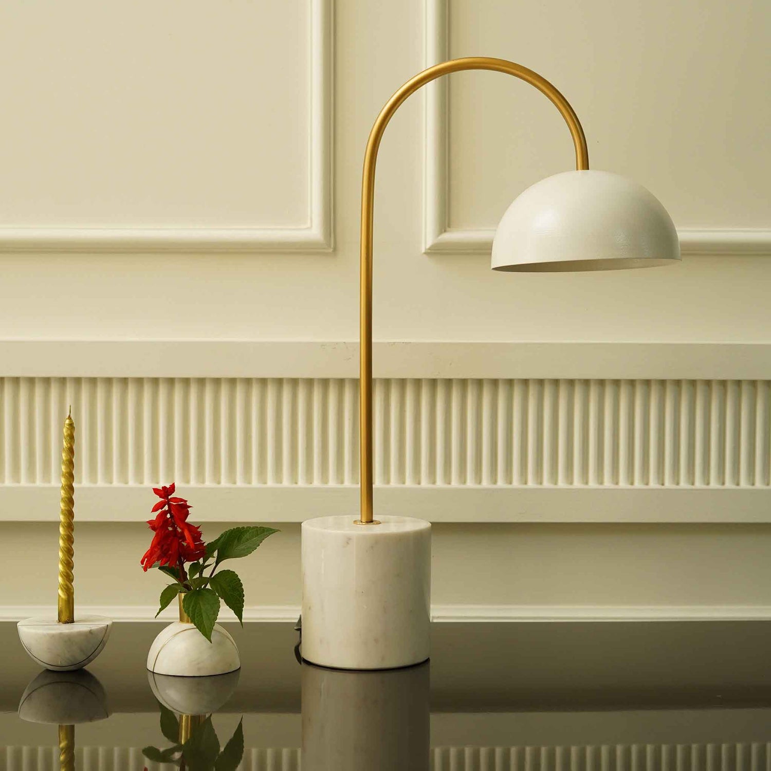 Cylindrical base white marble table lamp with golden curved stem and a white metallic shade.
