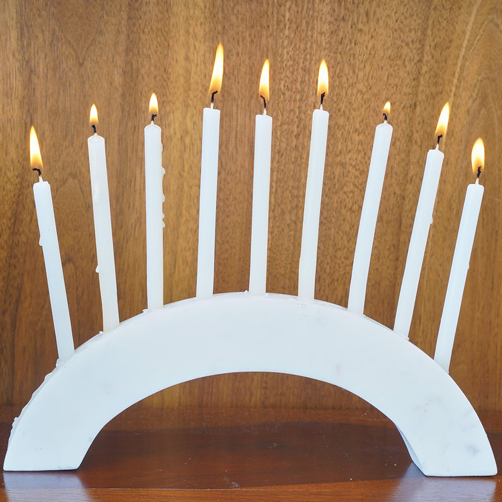 Front view of a white marble semi-circle slab as a candle holder with 9 burning candles.