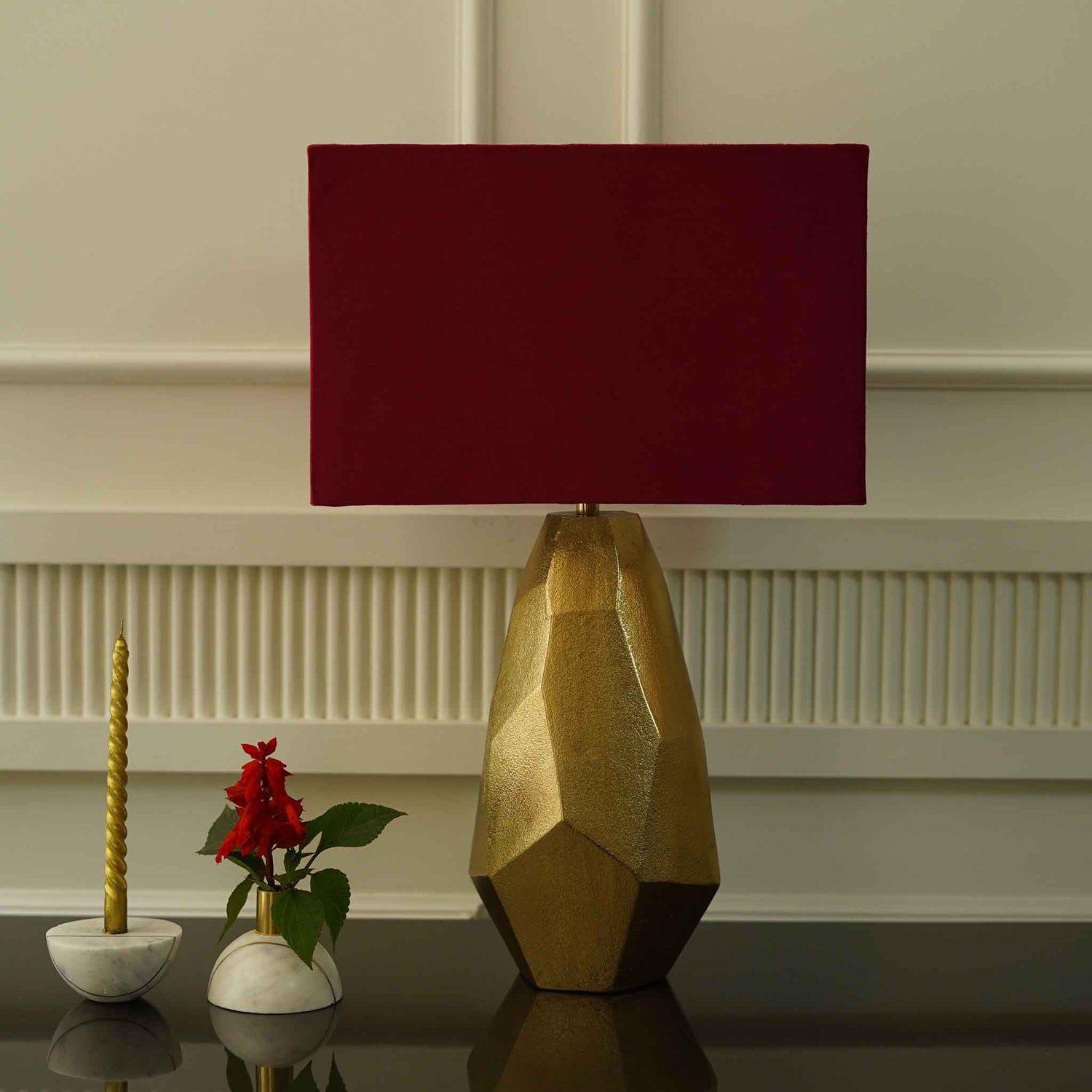 Golden color metallic textured table lamp with red lamp shade.